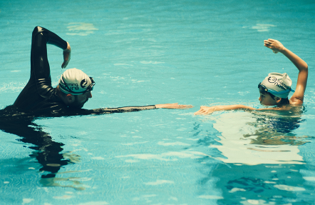 Female swimming instructor using a hands-on approach to train a young girl