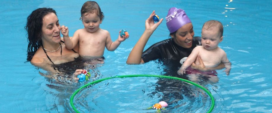 Female instructor supporting a baby in a pool during a swimming lesson