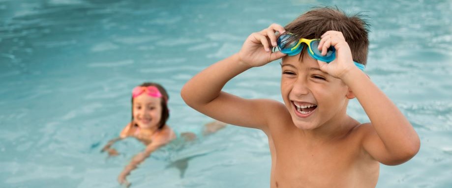 Female swimming instructor teaching a young girl water confidence using diving rings