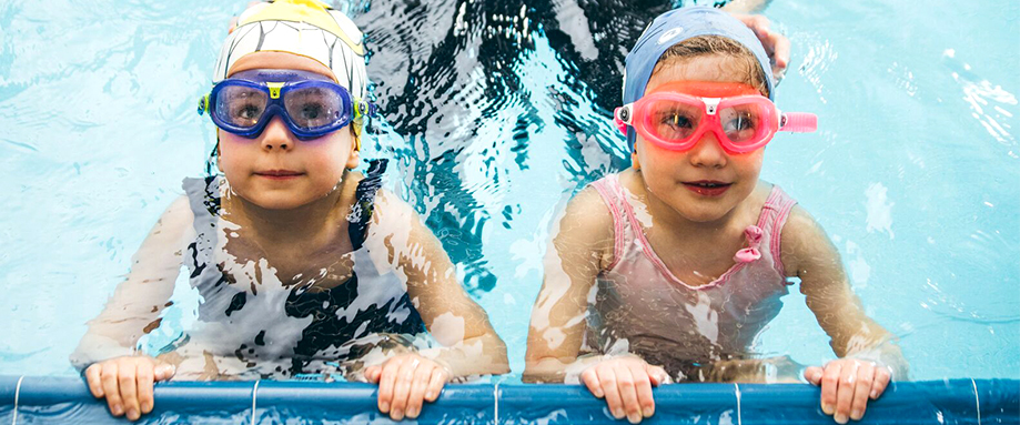 Young boy swimming frontcrawl with goggles and waterproof hat on