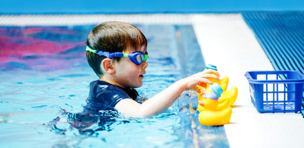 Three children being taught by their female swimming instructor in a pool